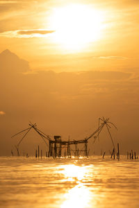 Silhouette cranes against sky during sunset