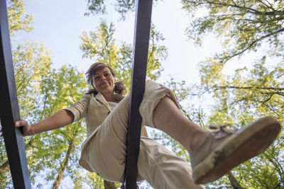Low angle view of smiling young man against trees