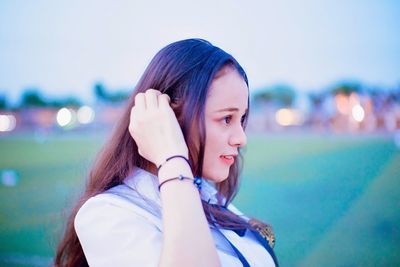 Close-up of young woman using mobile phone against sky