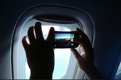 Cropped hand of person photographing from airplane