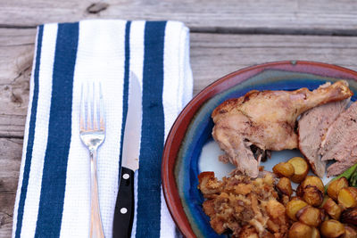 High angle view of roast chicken with vegetables served in plate on wooden table