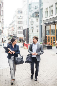 Male and female business professional talking while walking in city