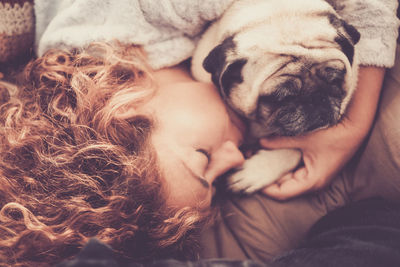 High angle view of woman sleeping with dog on bed at home