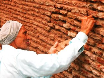 Side view of senior man touching stone wall