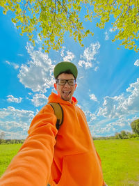 Portrait of young man standing on field against sky