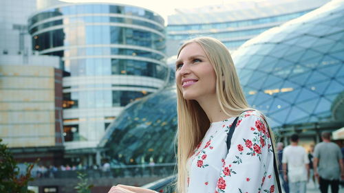 Smiling young woman looking up in city