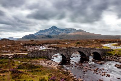 Arch bridge over mountains against sky