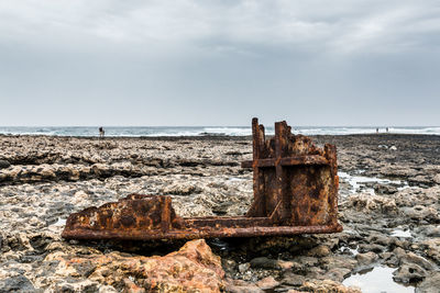 Rusty metal on beach against sky