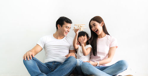 Young couple sitting against white wall