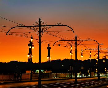 Silhouette street lights against orange sky