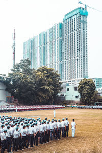 Group of people in front of buildings against clear sky