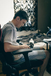 A young man repairs the engine steering wheel on a joystick.