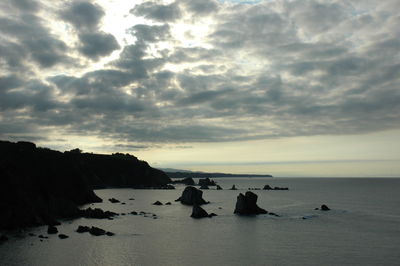 Rocks on beach against sky during sunset