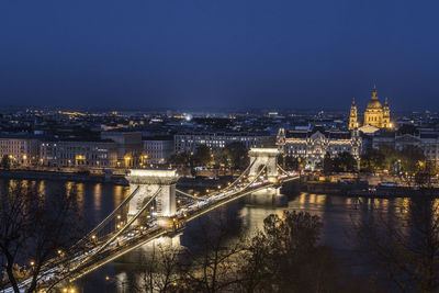 Illuminated bridge over river in city at night