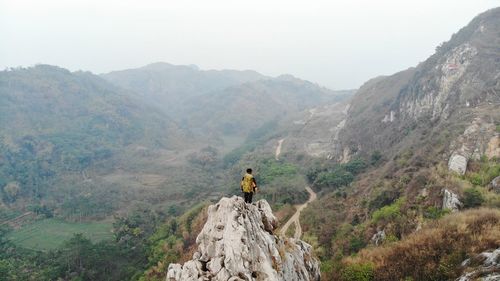 Man standing on rock against mountain range