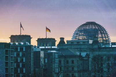 Reichstag and buildings in city at sunset