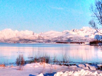 Scenic view of lake by snowcapped mountains against sky