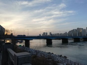 Bridge over river in city against sky