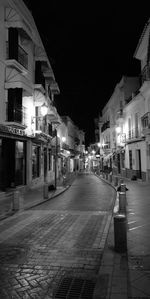 Empty street amidst buildings in city at night