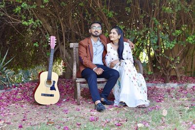 Full length portrait of young couple sitting outdoors