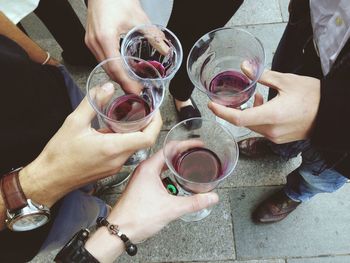 High angle view of people holding glasses with drink on street