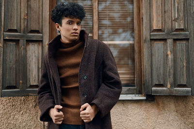 Portrait of young woman standing against wall