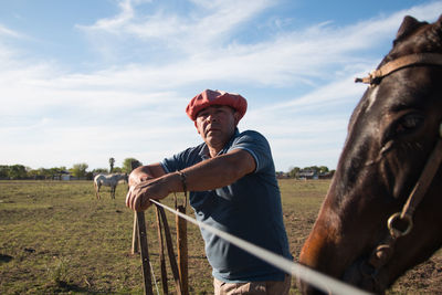 Man posing with his horse in field
