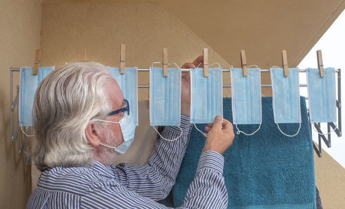 Side view of senior man drying surgical mask on clothesline