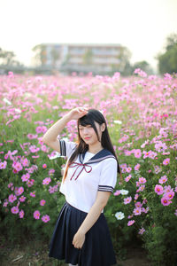 Woman standing by pink flowering plants