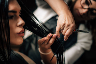 Close-up of hairdresser cutting woman hair in salon