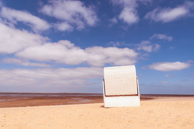 Hooded chairs on beach against sky