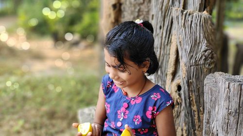 Little girl playing with fresh orange. blurred green background, copy space