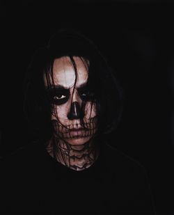 Close-up portrait of man with spooky halloween make-up against black background