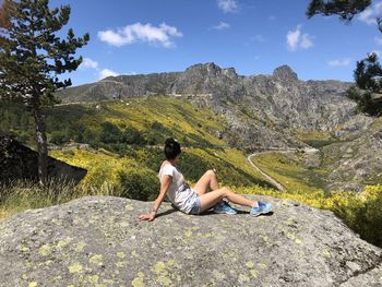 Man sitting on rock against mountains