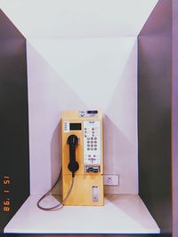 Close-up of telephone booth on table against wall