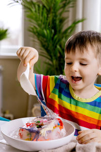 Happy boy pouring water on frozen toys at home