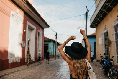 Rear view of woman walking on street amidst buildings