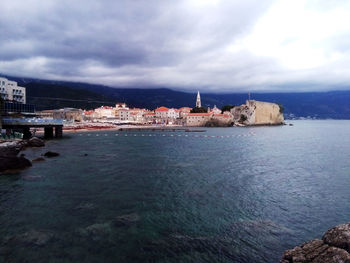 Buildings by sea against sky in city