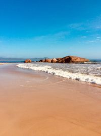 Scenic view of beach against blue sky