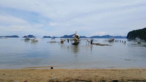 View of boats in lake against cloudy sky