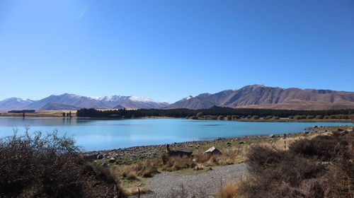 Scenic view of lake and mountains against clear blue sky