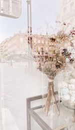 Flower vase on table against glass wall