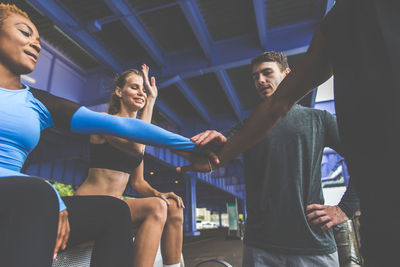 Friends stacking hands while standing under bridge