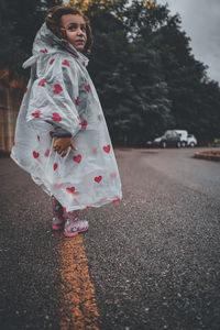 Full length of girl standing on road in city