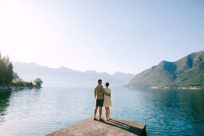 Rear view of friends on lake against mountains