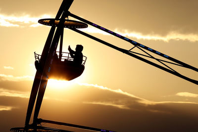 Low angle view of crane against sky at sunset