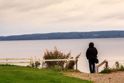 Rear view of woman standing by sea against sky