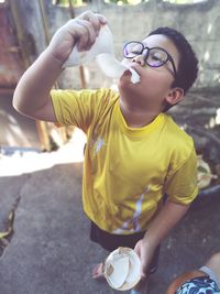 Full length of boy eating coconut while standing on footpath