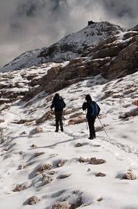 Rear view of people hiking on snow covered mountain