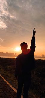 Low section of man holding hands against sky during sunset